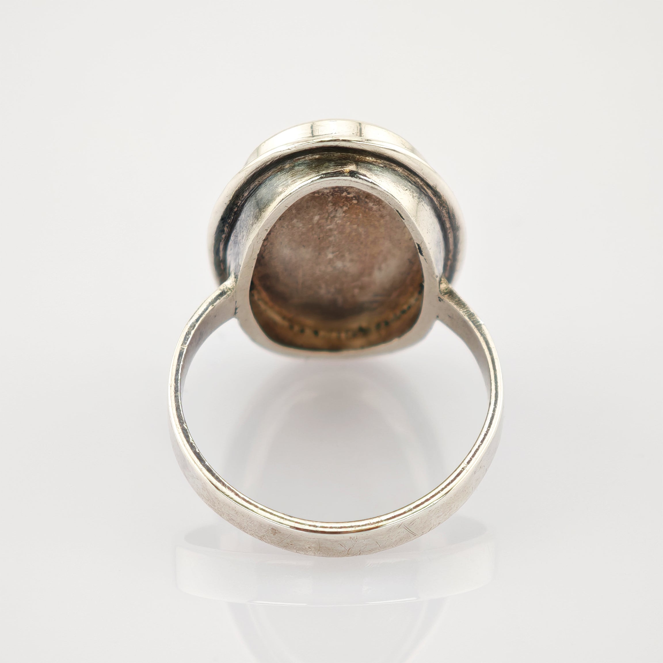 Silberner Ring mit glattem Band und sichtbaren Kratzern auf weißem Hintergrund