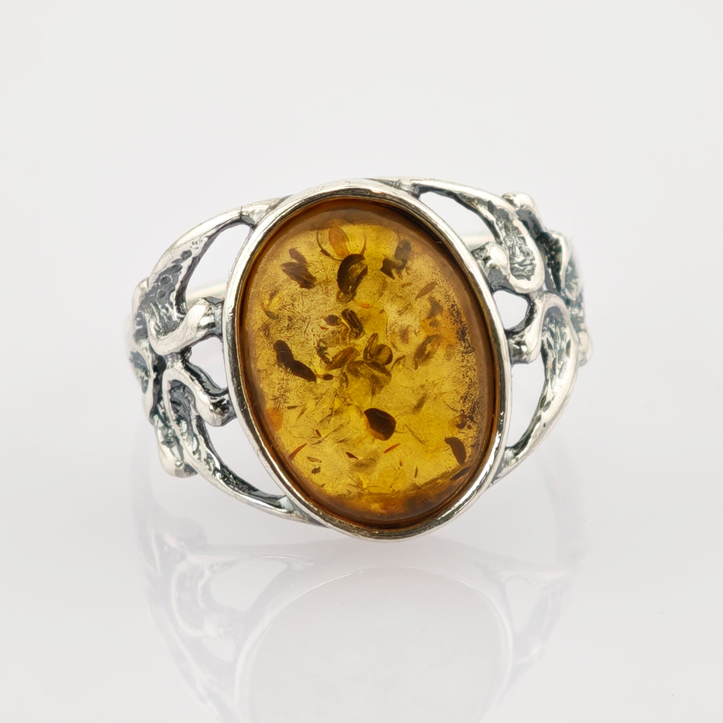 Nahaufnahme eines silbernen Rings mit ovalem bernsteinfarbenem Edelstein und organischen Details.