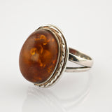 Eleganter silberner Ring mit großem ovalem Bernstein und gedrehtem Seildetail