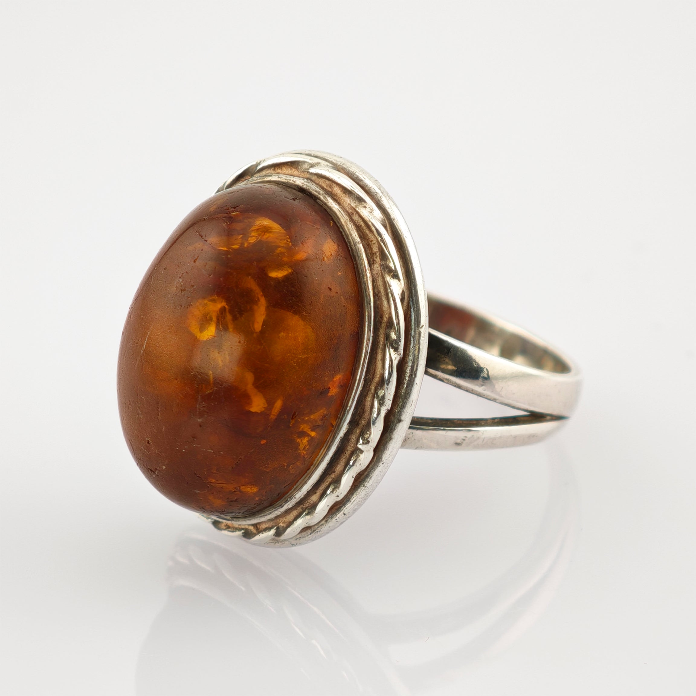 Eleganter silberner Ring mit großem ovalem Bernstein und gedrehtem Seildetail