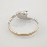 Silberner Ring mit ovalem Besatz und kleinen Perlen auf weißer reflektierender Fläche.