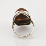 Silberner Ring mit ovalem braunem Stein und poliertem Metallband, seitliche Ansicht