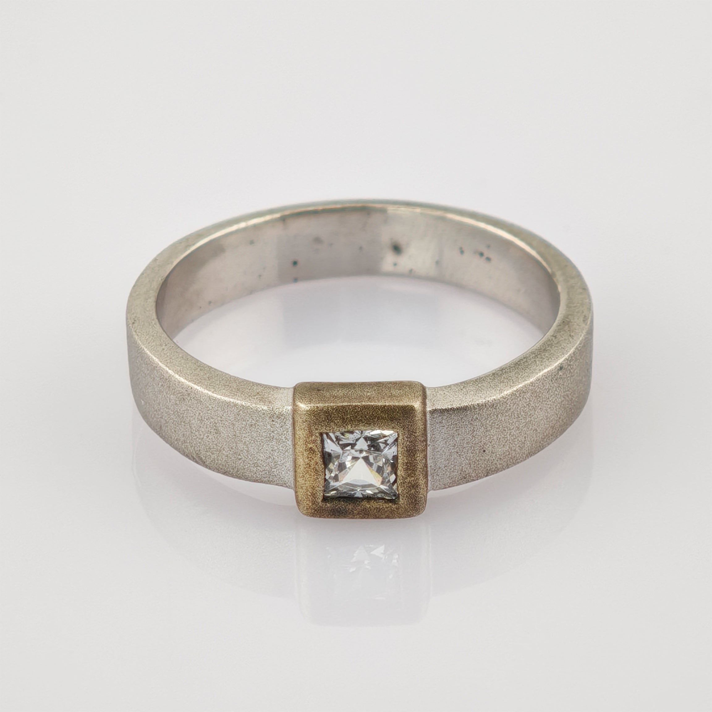 Silberner Ring mit quadratischer Fassung und klar geschliffenem Edelstein.