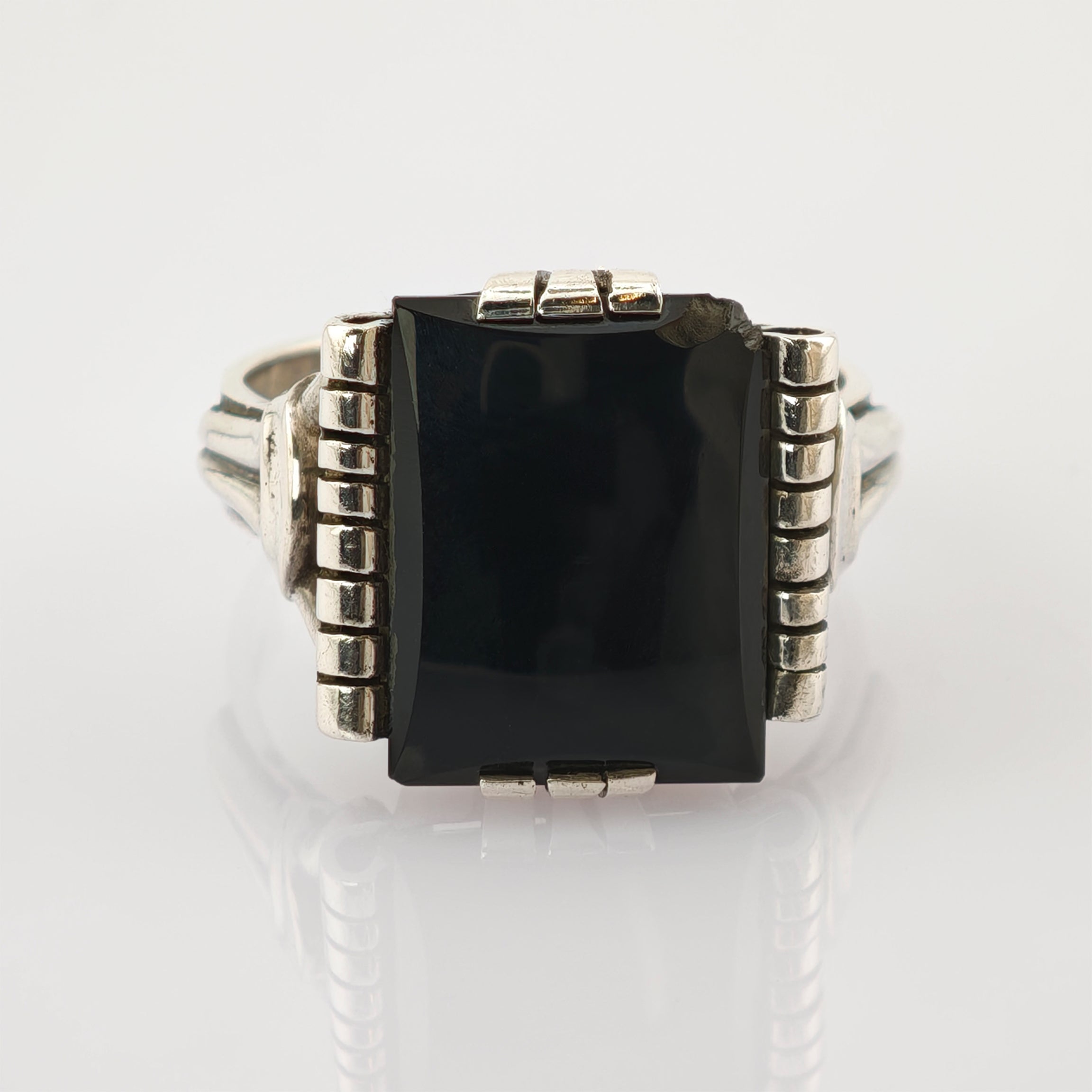 Silberner Ring mit großer rechteckiger schwarzer Steinfassung und geteiltem Ringband auf weißem Hintergrund