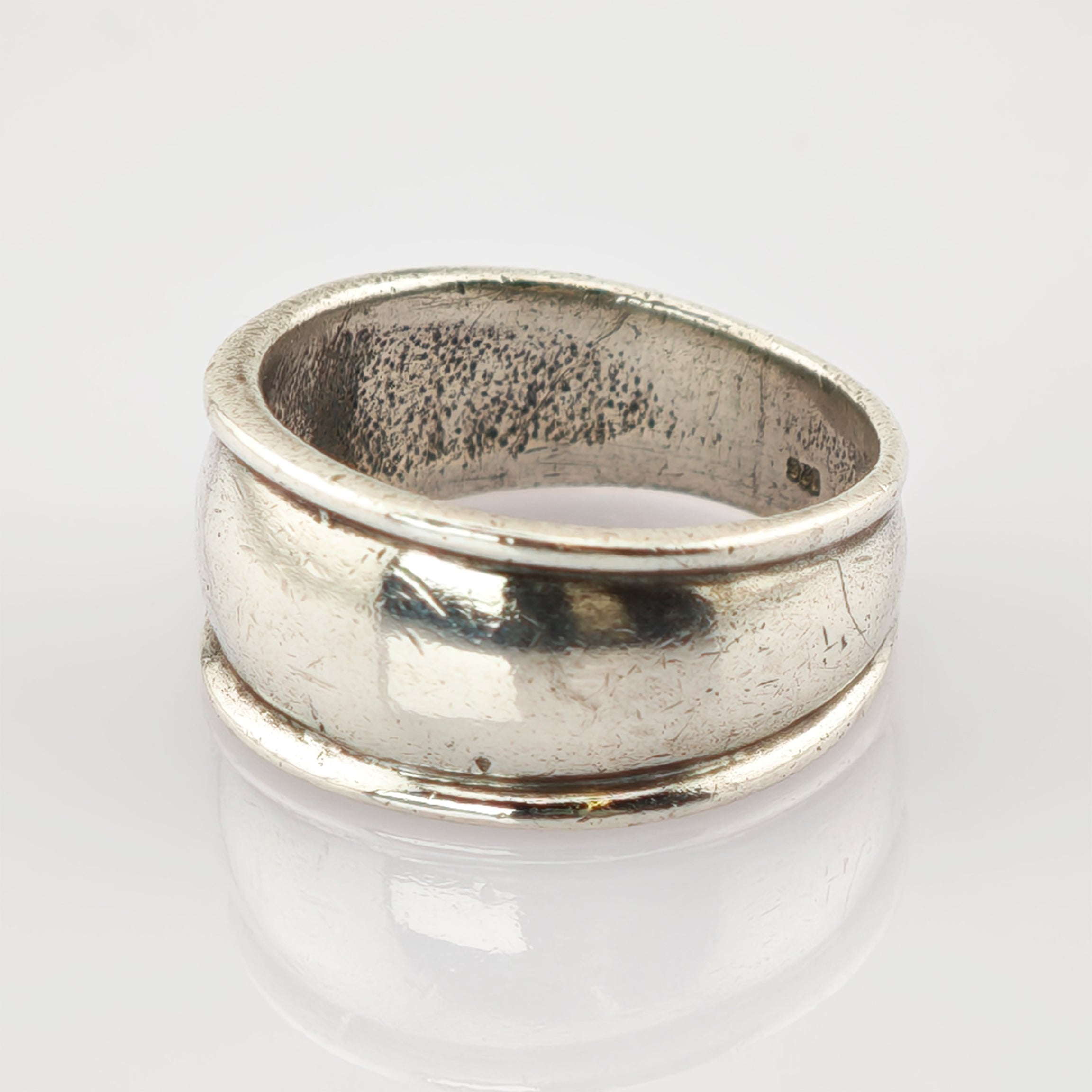 Schlichter silberner Ring mit rundem Band und texturierter Oberfläche vor weißem Hintergrund