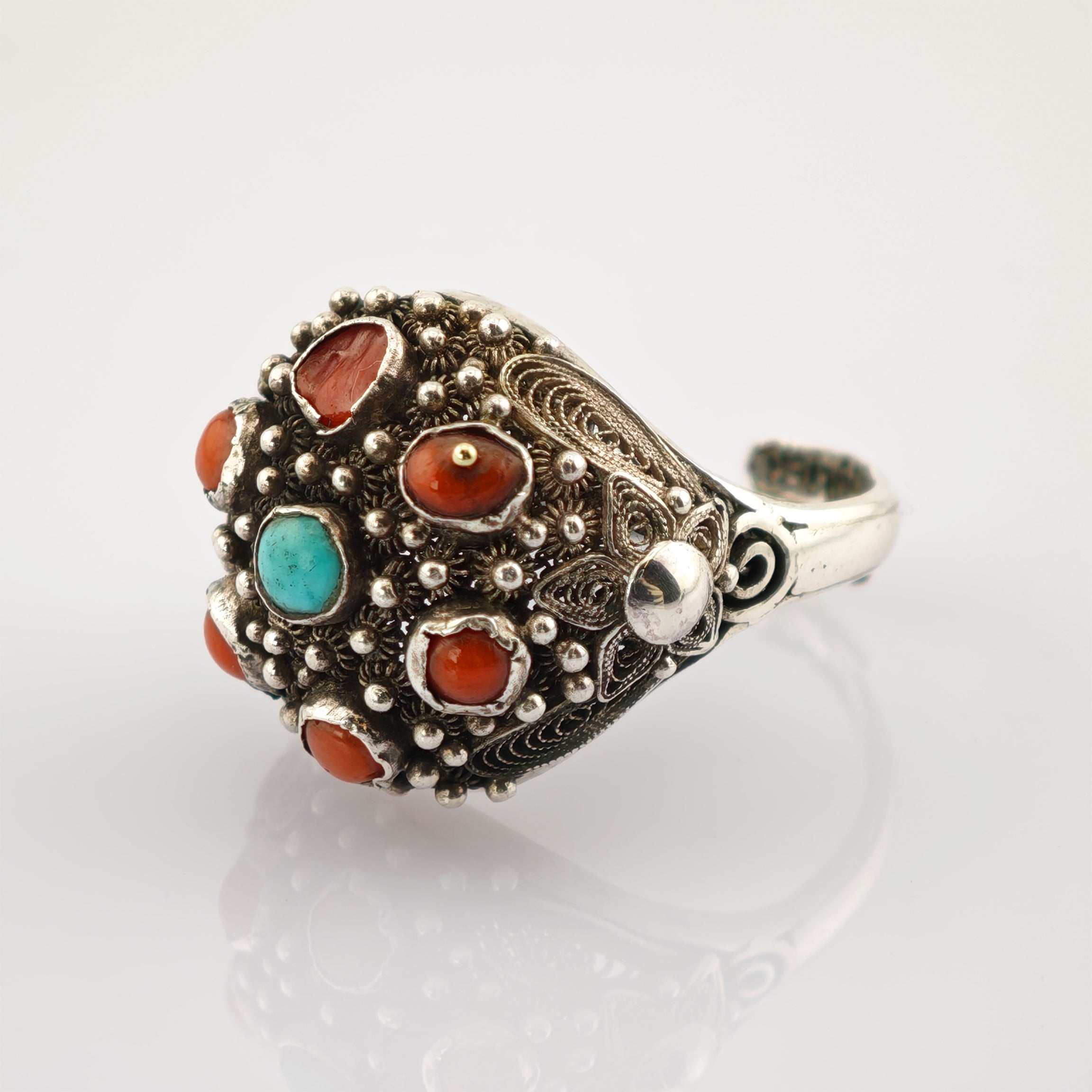 Silberner Ring mit zentralem Türkis und roten Steinen, verziert mit filigranen Details und Kugelakzenten