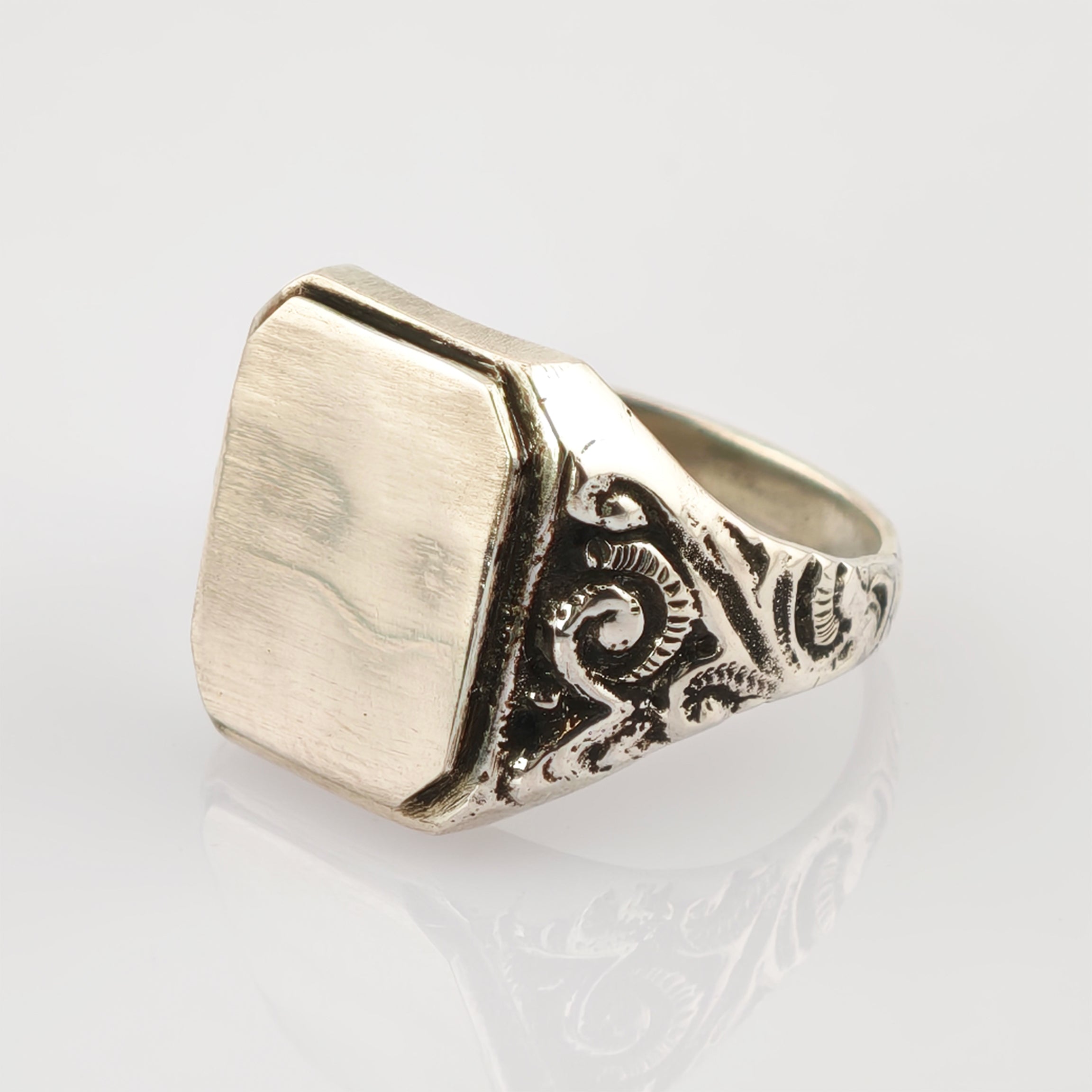 Silberner Siegelring mit oktogonalem flachen Gesicht und Gravuren auf weißem Hintergrund