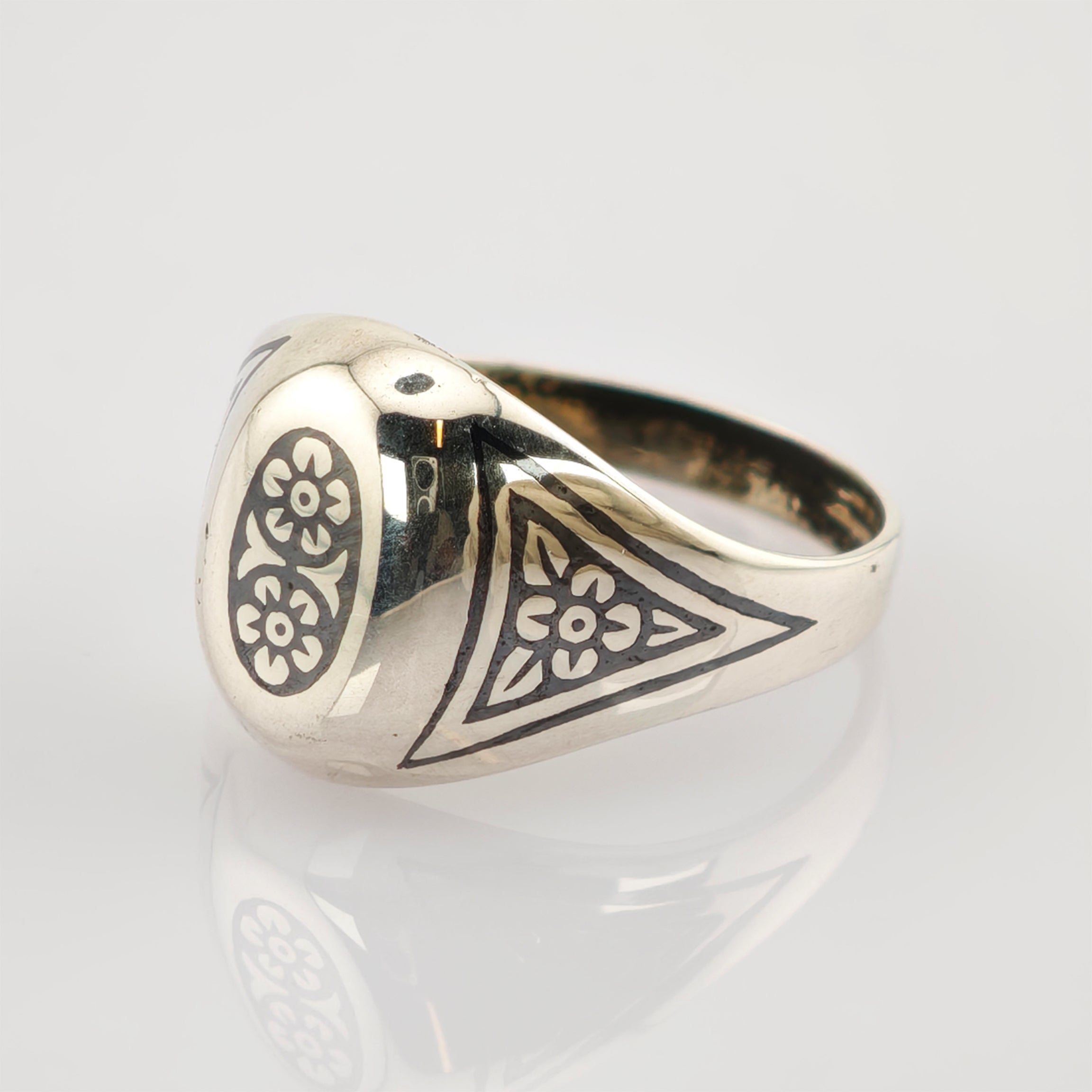 Silberner Siegelring mit schwarzen floralen Gravuren und der Zahl 7 auf weißem Hintergrund