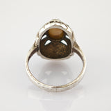 Silberner Vintage-Ring mit detaillierten Verzierungen und glänzendem Gehäuse aus Metall.