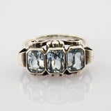 Silberner Vintage-Ring mit drei rechteckigen hellblauen facettierten Steinen und filigranen Metallarbeiten.