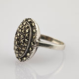 Silberner Vintage-Ring mit ovalem Gesicht und strukturiertem Design, besetzt mit kleinen goldfarbenen Steinen.