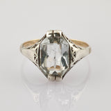 Silberner Vintage-Ring mit Gravuren und rechteckigem Edelstein auf grauem Hintergrund