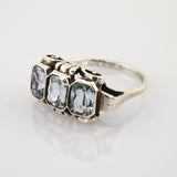 Silberner Vintage-Ring mit drei rechteckigen klaren Edelsteinen auf weißem Untergrund.