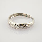 Silberfarbener Edelstahlring mit eingravierten Stern- und Blumenmustern auf der abgerundeten Oberfläche.