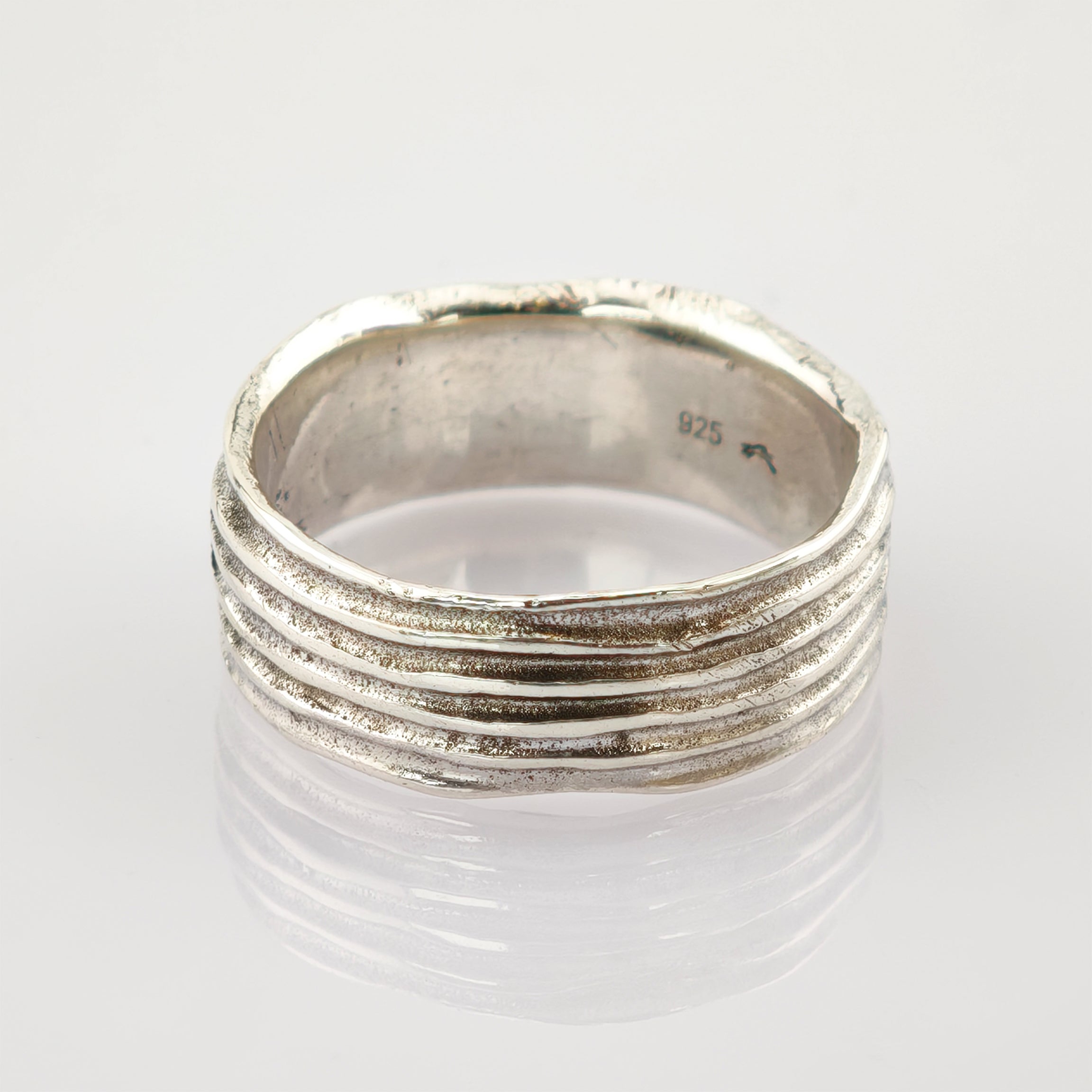 Silberring mit fünf horizontalen Erhebungen und 925er Silberstempel auf reflektierender weißer Oberfläche