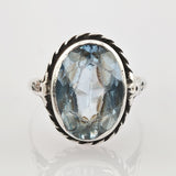Silberring mit gedrehtem Band und ovalem blauem facettiertem Edelstein mit inneren Einschlüssen