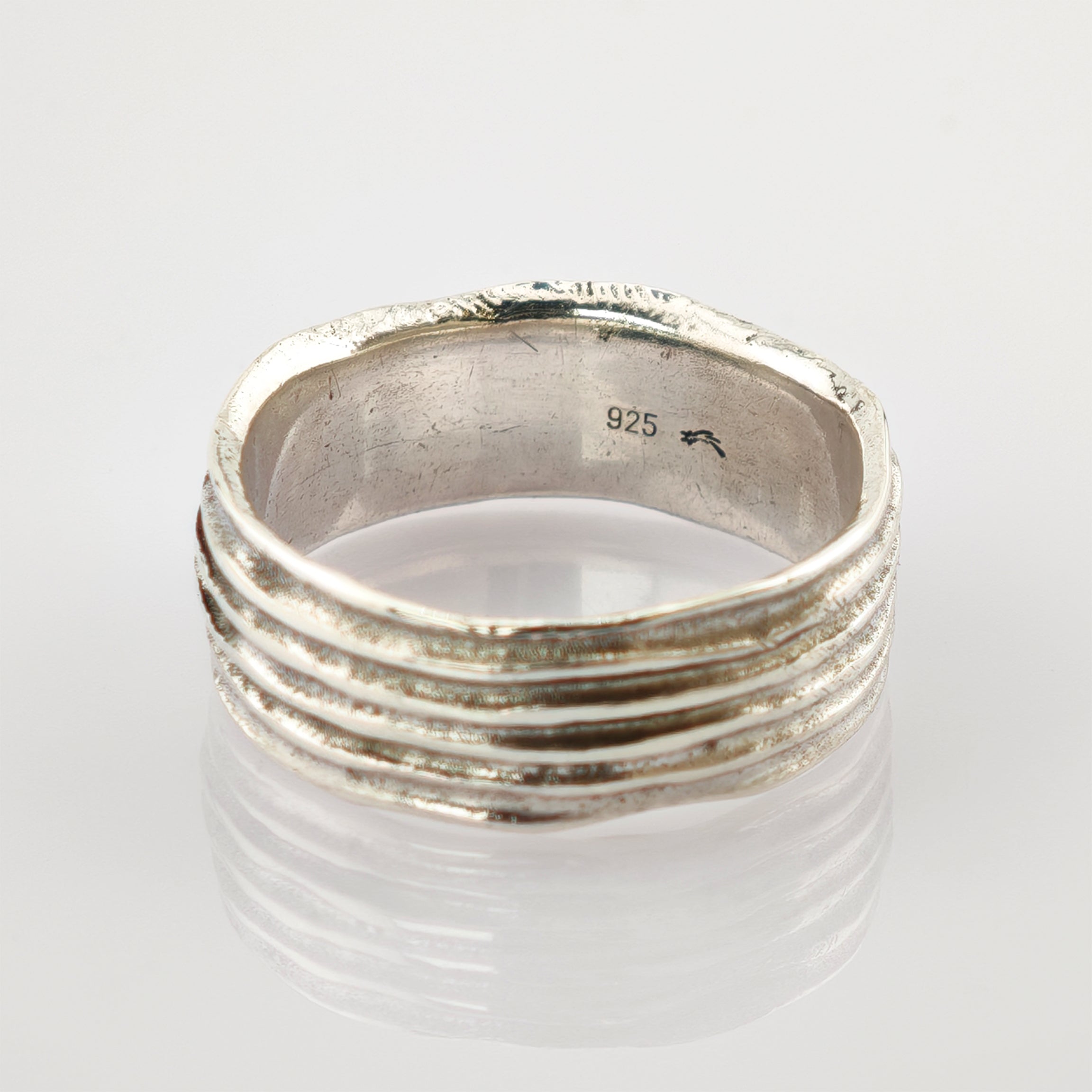 Silberring mit strukturiertem, geripptem Design und 925-Stempel auf reflektierender Oberfläche