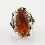 Silberring mit großem, marquiseförmigem Bernstein in leuchtendem Orange-Braun und dekorativem Seildesign.