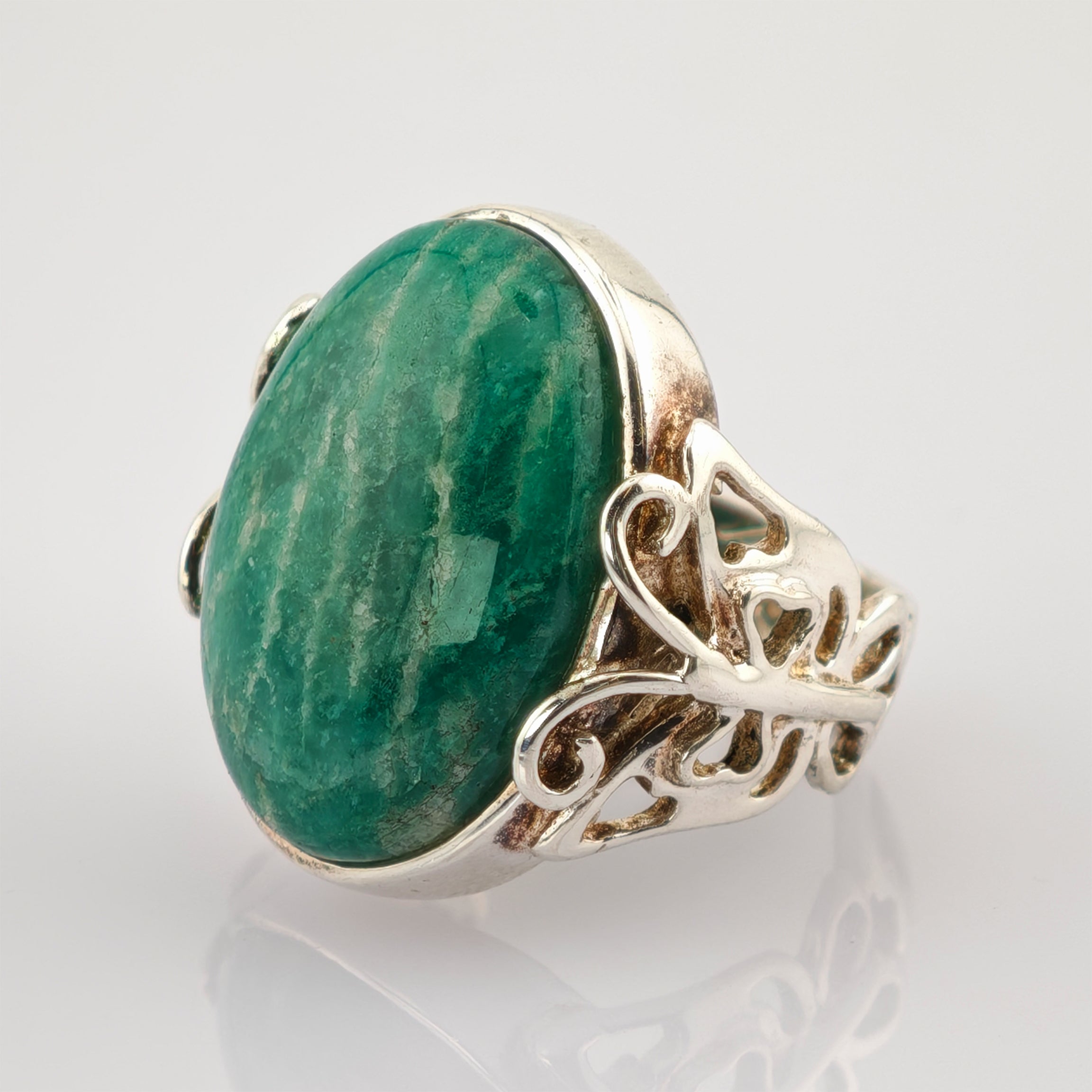 Detailaufnahme eines silbernen Rings mit großem ovalem grünen Edelstein und feiner filigraner Verzierung