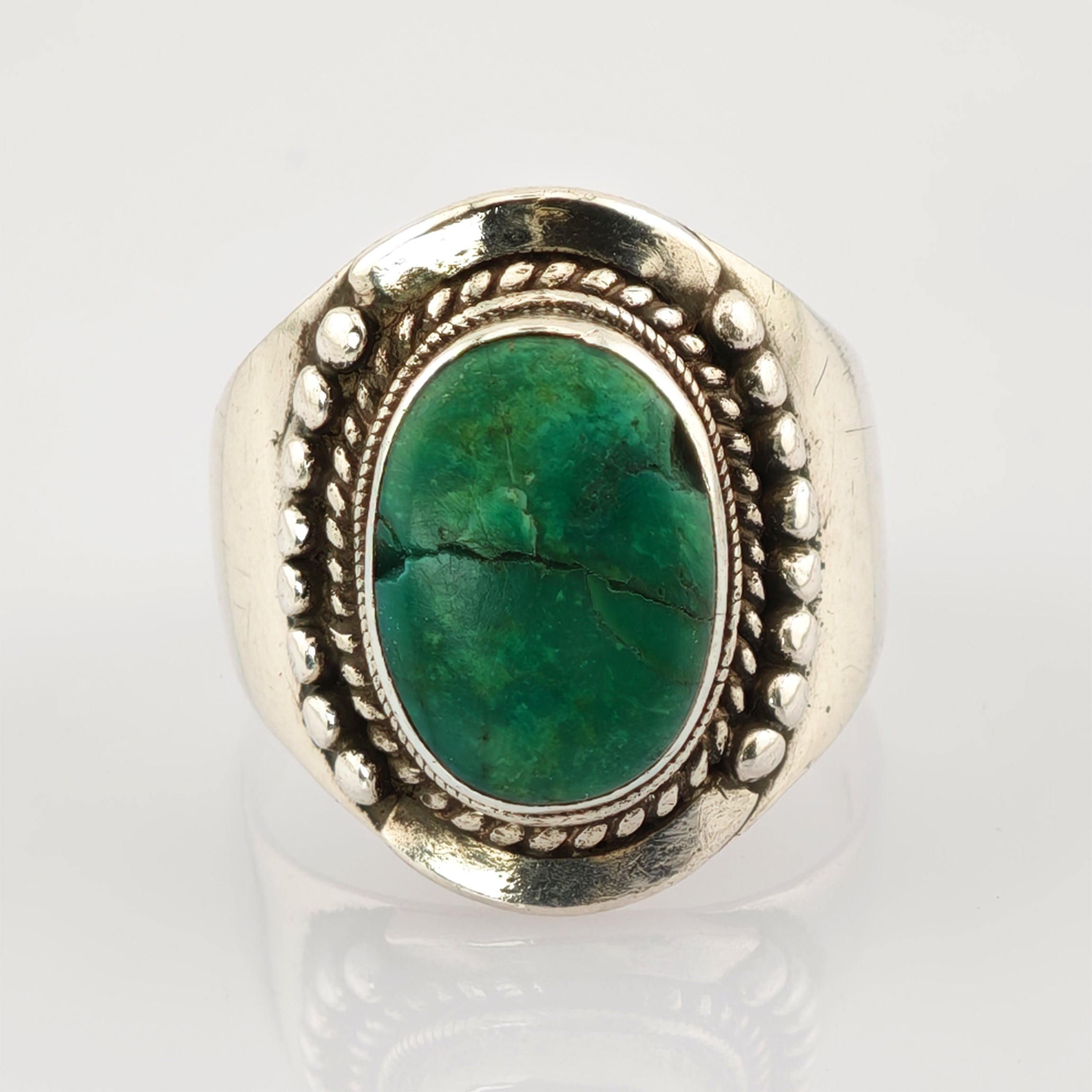 Silberring mit ovalem grünem Edelstein und dekorativen Details.
