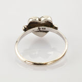 Silberring mit Herzform und 925-Punze, sichtbare Kratzer und Anlaufspuren, auf weißem Hintergrund.