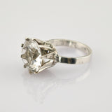 Silberring mit großem klarem facettiertem Schmuckstein in Krappenfassung auf reflektierendem Untergrund