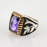 Silberring mit großem lila Edelstein und goldfarbenem Fassungsrand, verziert mit schwarzen Emaille-Floralmustern.