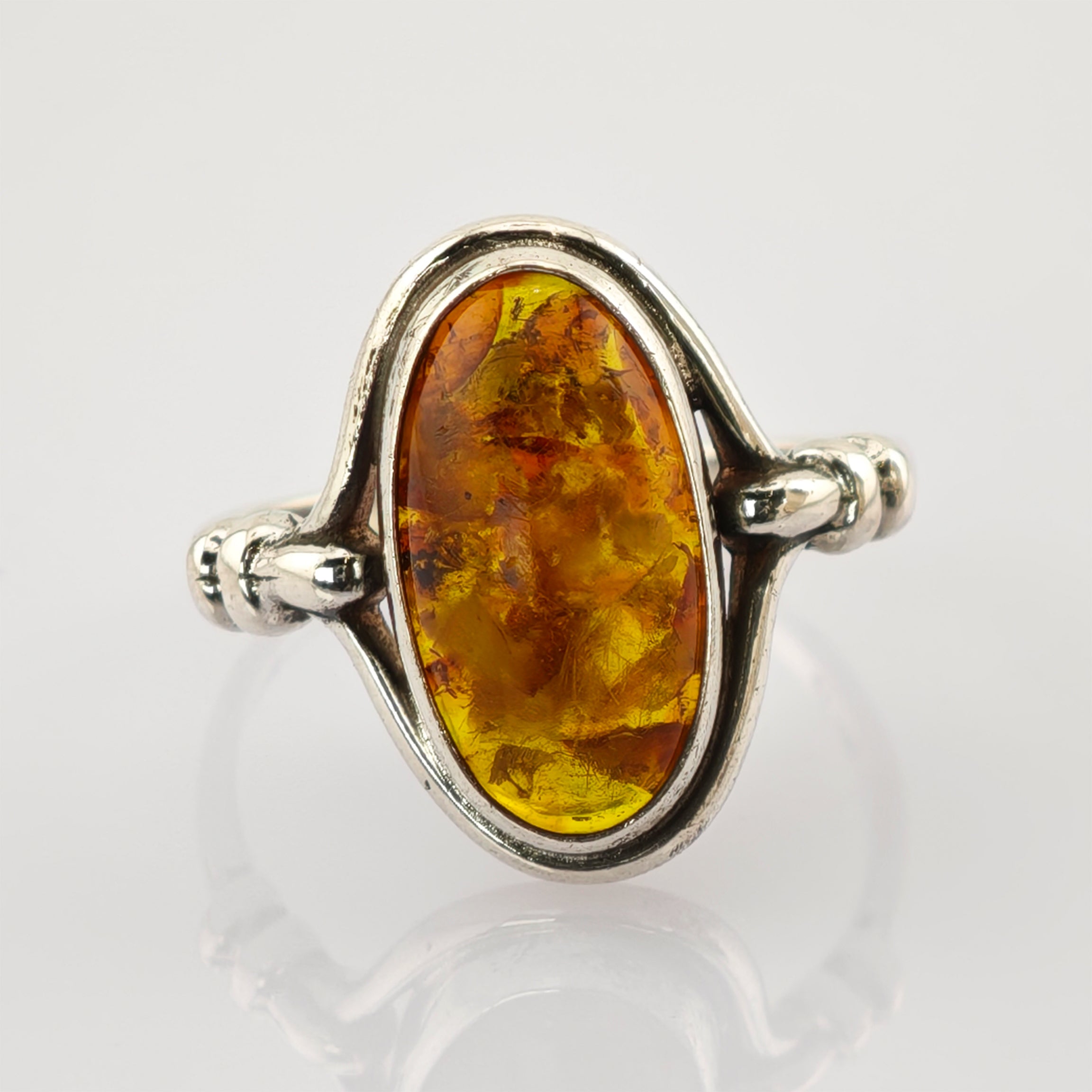 Silberring mit großem ovalem Bernstein in warmen Gelb- bis Orange-Tönen und Verzierungen am Ringband