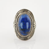 Silberring mit ovalem blauem Edelstein und Seil- und Perlenmuster auf weißem Hintergrund