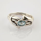 Silberring mit ovalem blauem Edelstein und geschwungenem Band, 925 Sterlingsilber.