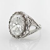 Silberring mit oval facettiertem klarem Edelstein und Seildesign im Vintage-Stil auf reflektierendem Untergrund.