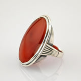 Silberring mit großem ovalem polierten Karneolstein und geriffeltem Band auf weißem Hintergrund