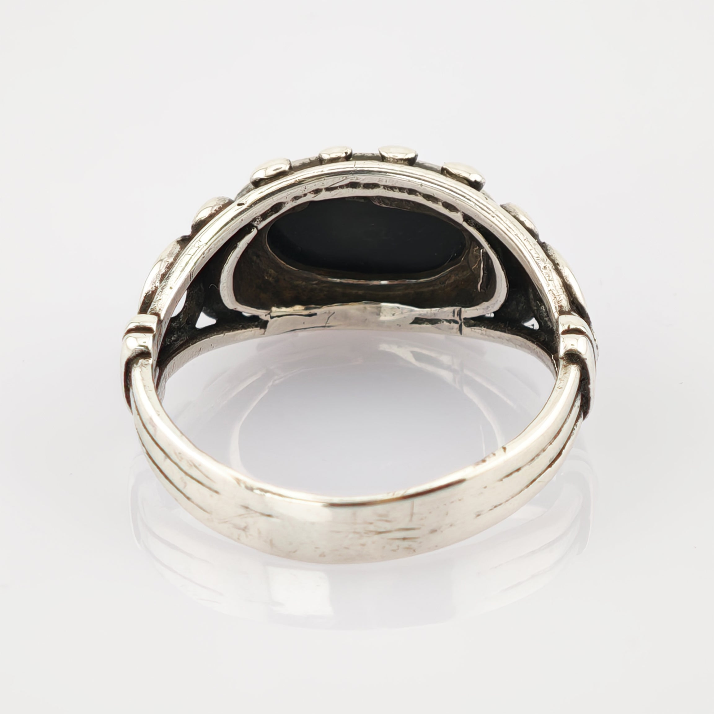 Silberring mit ovalem schwarzen Stein und Verzierungen auf weißem Hintergrund