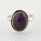 Silberring mit ovalem, tiefviolettem Stein in schlichter Fassung auf weißem Hintergrund