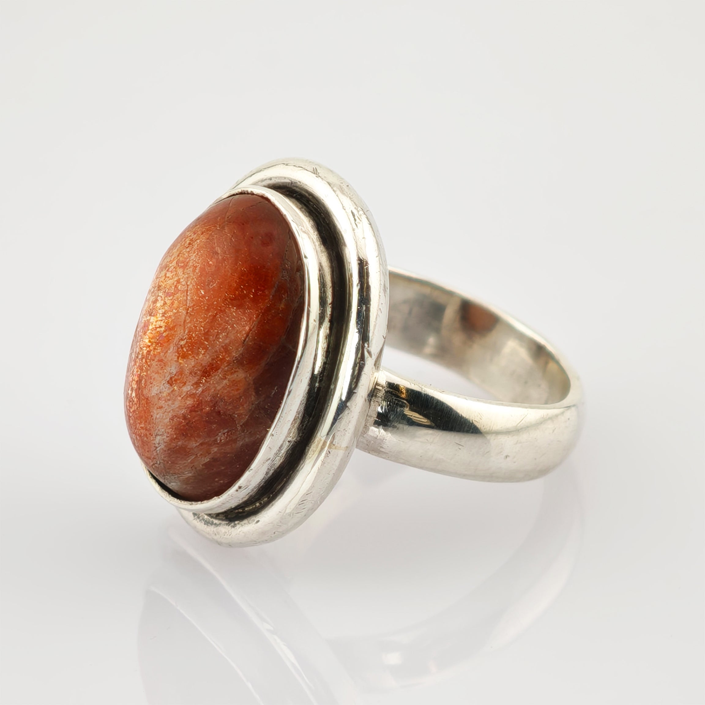 Silberring mit breitem poliertem Band und großem ovalem Cabochon in rötlich-brauner Zargenfassung