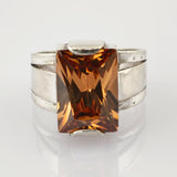 Silberring mit rechteckigem, facettiertem bernsteinfarbenem Edelstein und rustikalem Band.