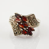 Silberring mit kunstvollem Design und roten markisenförmigen Steinen im Blattmuster, goldene Perlenakzente am Band