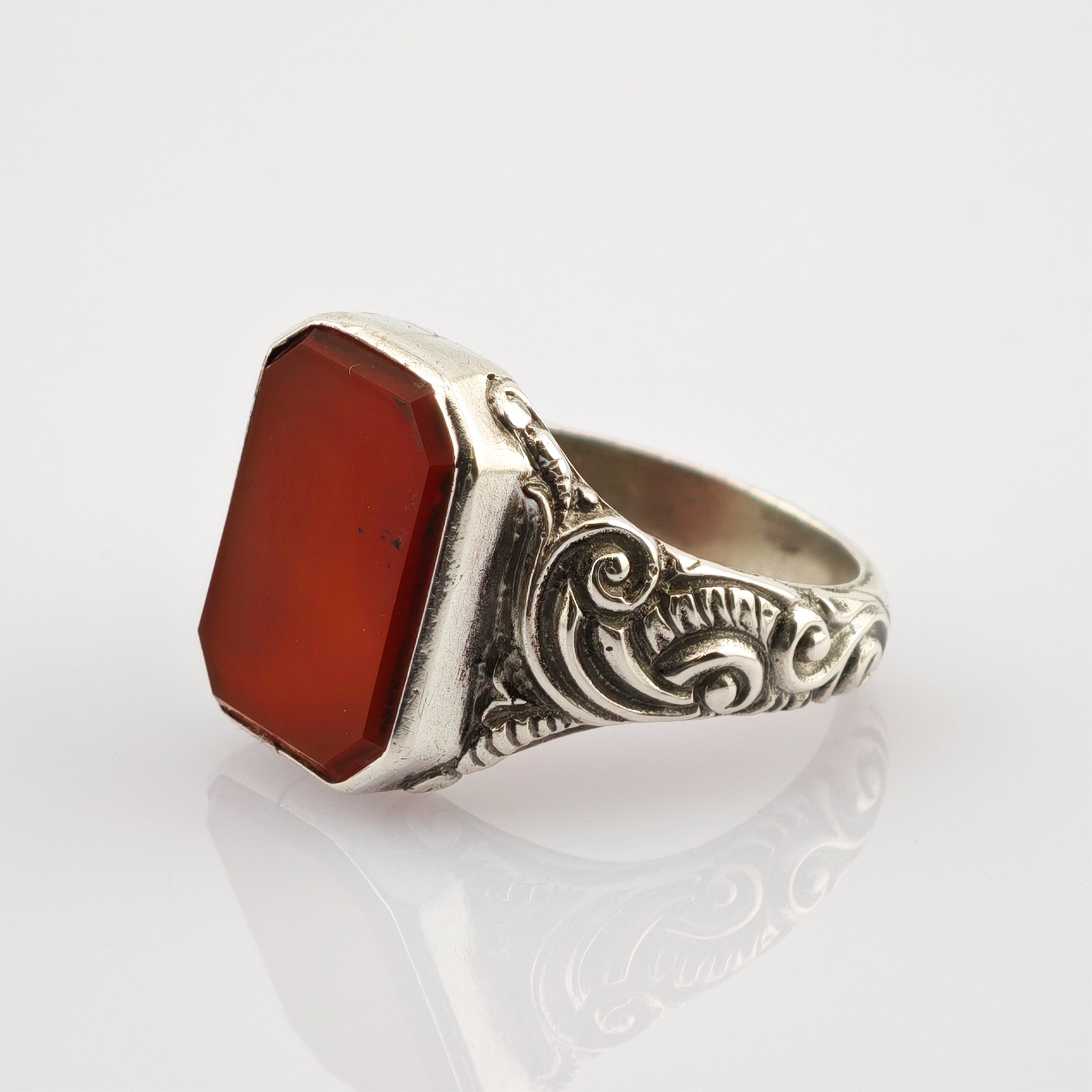 Silberring mit kunstvollen Schnörkelmustern und großem, rot-oktogonalem Edelstein in der Mitte.