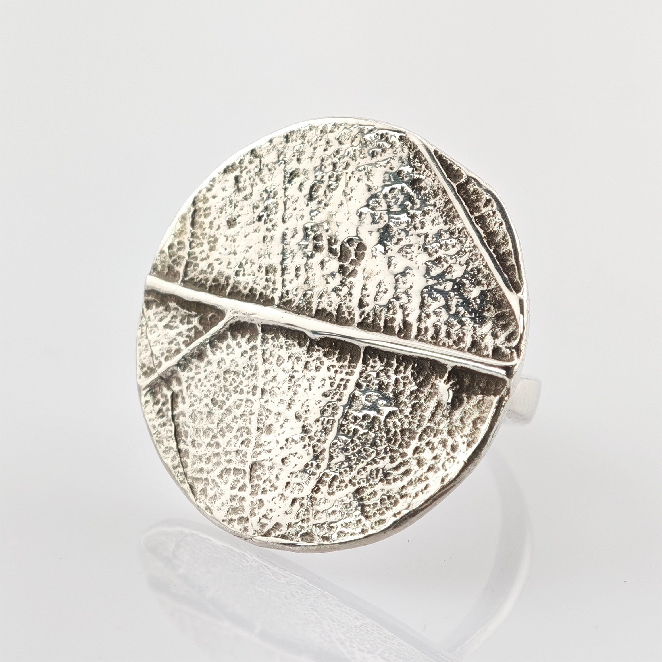 Silberring mit rundem flachen Top und Blattstruktur mit detaillierten Adern und matter Oberfläche.