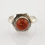 Silberring mit sechseckiger Fassung und feinen Verzierungen, mittig ein polierter, rötlich-brauner Edelstein.