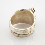 Silberring mit strukturierter Oberfläche im Steinmuster vor reflektierendem weißen Hintergrund.