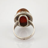 Sterlingsilberring mit ovalem orangem Edelstein und eingravierter 925-Punze auf glänzendem Band.