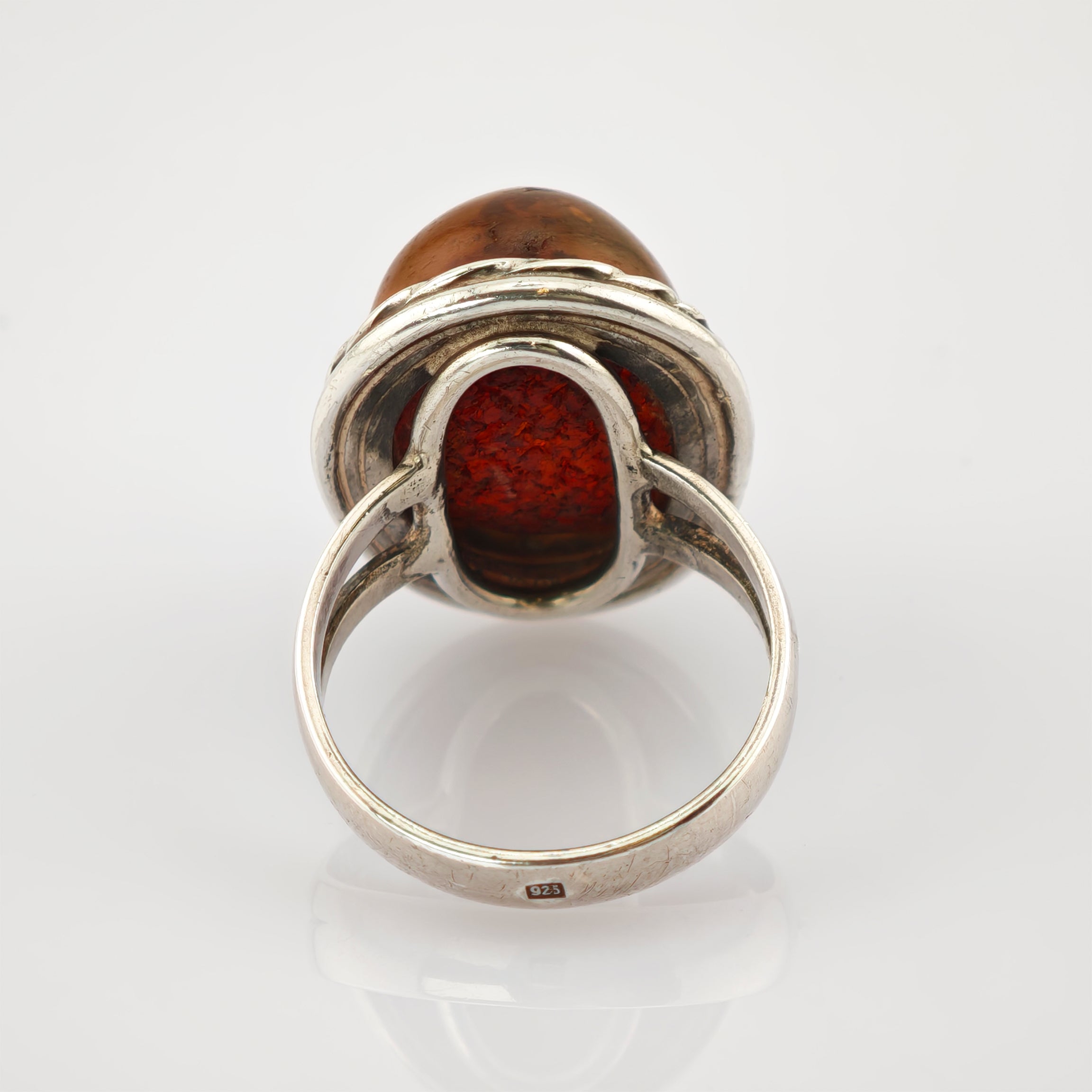 Sterlingsilberring mit ovalem orangem Edelstein und eingravierter 925-Punze auf glänzendem Band.