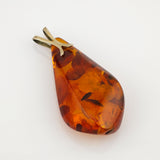 Tropfenförmiger Bernsteinanhänger mit natürlichen Einschlüssen und Metallöse auf weißem Hintergrund