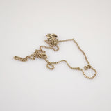 Verheddertes Goldkettchen mit verdrehten Gliedern und rundem Verschluss auf weißem Hintergrund