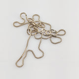 Verwickelte Goldkette mit Kastengliedern und rundem Verschluss auf weißem Hintergrund