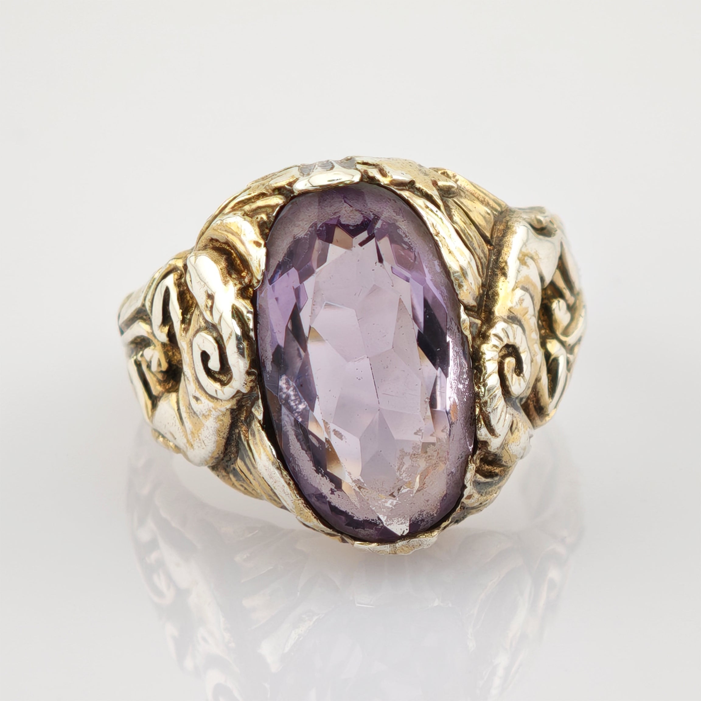 Vintage-Goldring mit großem ovalem, violettem facettiertem Edelstein und geschnitztem Band mit Blatt- und Wirbelmustern.