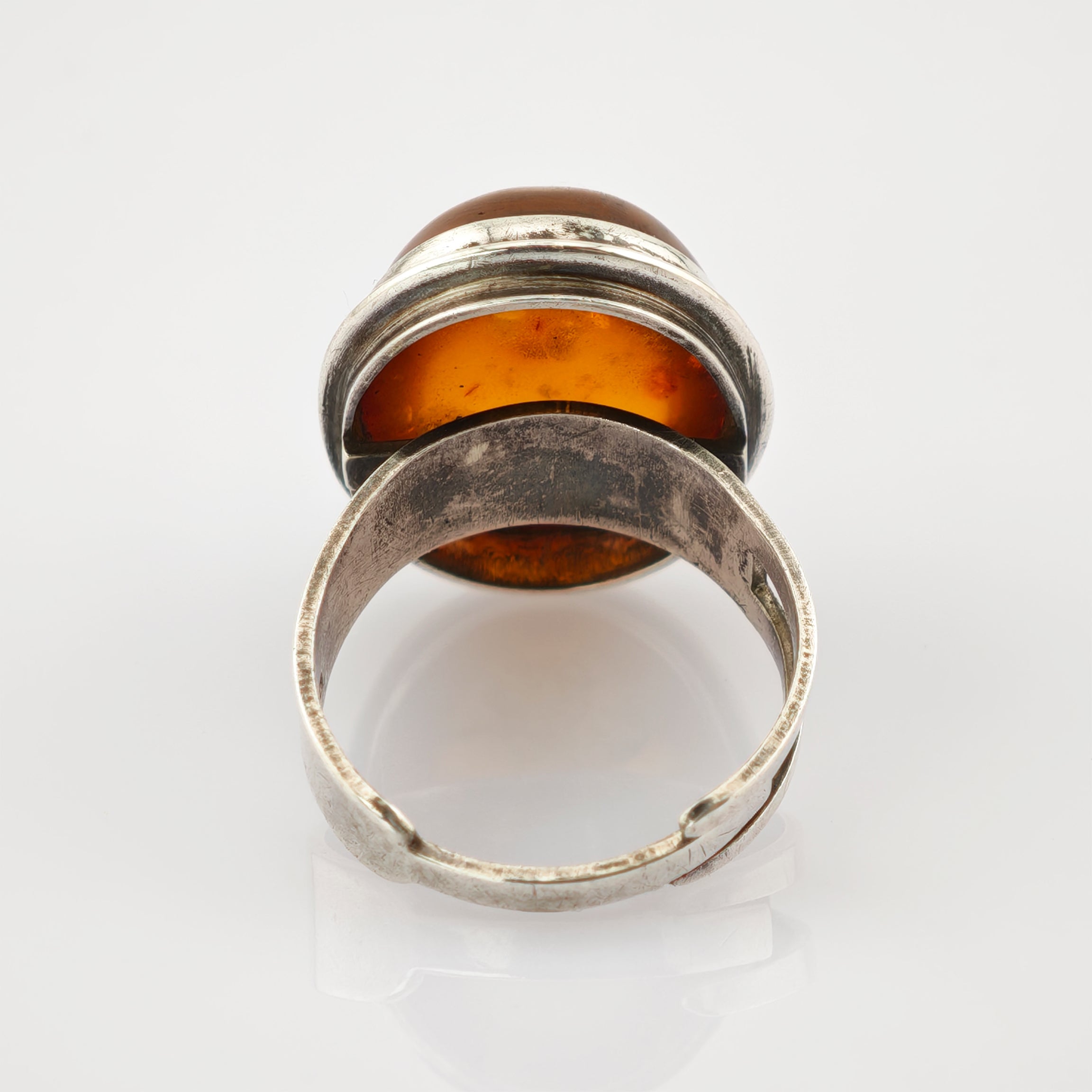 Vintage-Silberring mit bernsteinfarbenem Stein und verstellbarem Band auf weißem Hintergrund