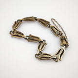 Vintagearmband aus miteinander verbundenen metallischen Blumelementen mit dunkler Patina und Sicherheitskette.