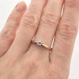 Weibliche Hand mit natürlicher Hautstruktur und zartem Goldring mit rundem Diamant-Solitär am Ringfinger